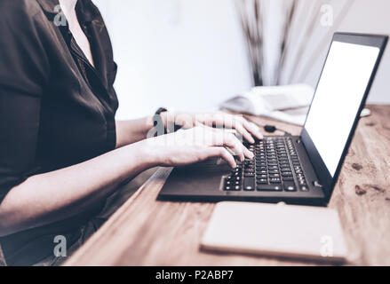 close-up of young woman working on laptop computer on wooden desk Stock Photo
