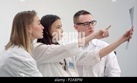 Three young doctors looking at spine x-ray Stock Photo