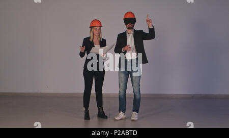 Two construction engineers in helmets with VR goggles managing building project in 3d Stock Photo