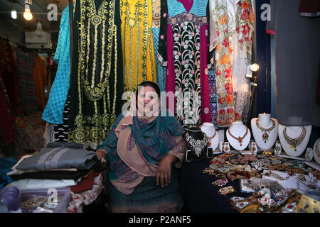 Manchester, UK. 14th June 2018. A Muslim women sat in her market store as celebrations take place for Chaand Raat, which translated literally means night of the moon.  The festival marks the end of Ramadam and the night before Eid. Longsight Market, Manchester, 14th June, 2018 (C)Barbara Cook/Alamy Live News Stock Photo