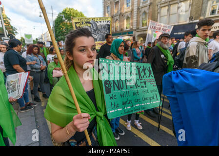 London, UK. 14th June 2018. A woman holds a poster 'No Justice No Peace' as she walks with thousands in silence along Ladbroke Grove remembering the victims of the disaster on the first anniversary of the disastrous fire which killed 72 and left survivors traumatised. Many of those made homeless by the fire are still in temporary accomodation a year later despite promises mde by Theresa May and Kensington & Chelsea council, who many fell have failed the local community both before and after the fire.  call for Credit: Peter Marshall/Alamy Live News Stock Photo