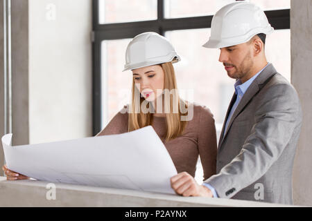 architects with blueprint and helmets at office Stock Photo