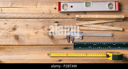 Carpentry tools. Measure tape, spirit level and rulers on wooden background, copy space, top view Stock Photo