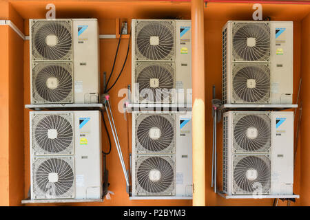 A stack of air conditioner condensers outdoor driving multiple air conditioners indoors on a hot day. Stock Photo