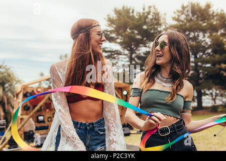 Hipsters with dancing ribbon stick at music festival. Two young women enjoying at music festival. Stock Photo