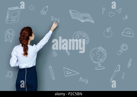 Clever teacher explaining a new topic and writing on the blackboard Stock Photo