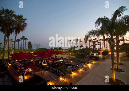 Garden restaurant with palm trees and sea after sunset in the Le Meridien Hotel, Limassol, Limassol District, Cyprus Stock Photo