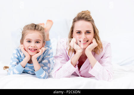 mother and daughter resting chins on hands and looking at camera at home Stock Photo