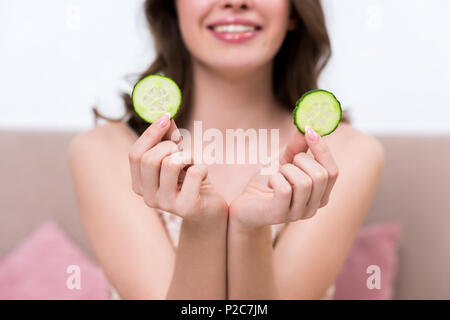 cropped shot of smiling young woman holding cucumber slices Stock Photo