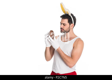Man with bunny ears holding chocolate egg isolated on white, easter concept Stock Photo