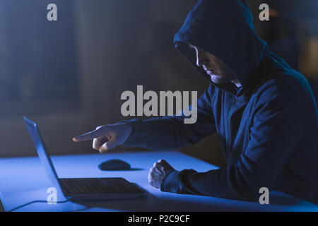 hacker pointing at laptop computer in dark room Stock Photo