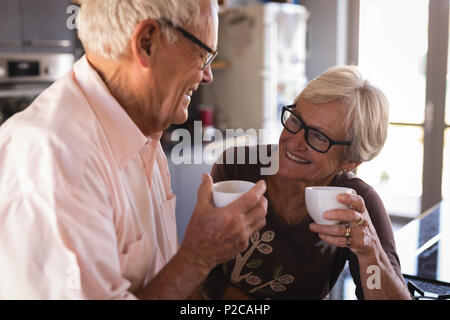 Senior couple smiling while having coffee in kitchen Stock Photo
