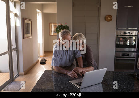 Senior couple video calling on laptop in kitchen Stock Photo