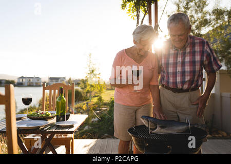 Senior couple cooking fish on barbeque Stock Photo