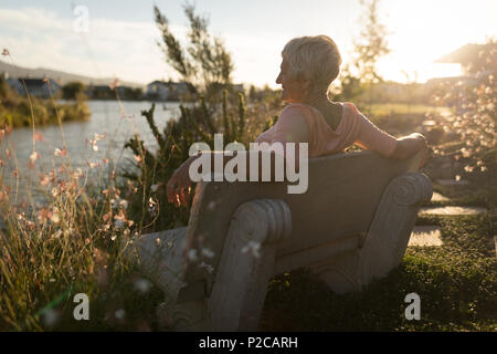 Senior woman relaxing on bench near riverside Stock Photo