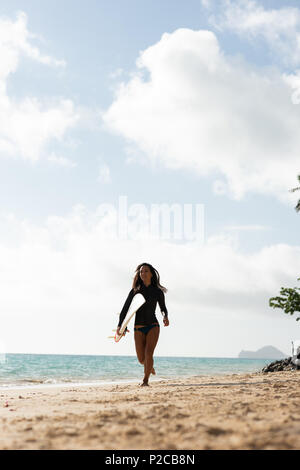Woman running with surfboard in the beach Stock Photo