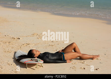 Woman sleeping on surfboard in the beach Stock Photo