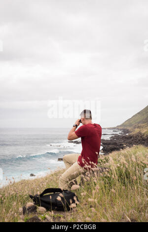 Man looking through binoculars in countryside Stock Photo