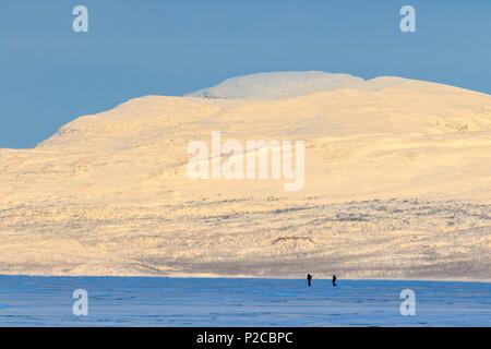 Sweden, Lapland, region listed as World Heritage by UNESCO, Norrbotten County, View of skiers at sunrise on Lake Tornetrask in the vicinity of Abisko National Park Stock Photo