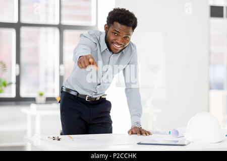 african architect with blueprint pointing at you Stock Photo