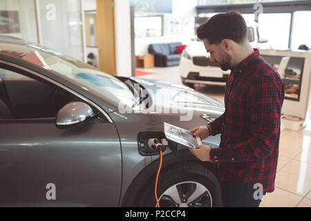 Salesman standing next to car and reading brochure Stock Photo