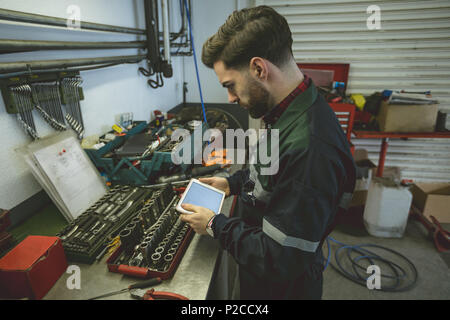 Mechanic using digital tablet at work bench Stock Photo