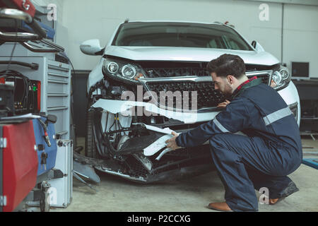 Mechanic examining damaged car Stock Photo