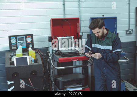 Attentive mechanic using mobile phone Stock Photo