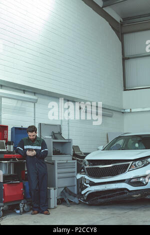 Mechanic using mobile phone while repairing car Stock Photo