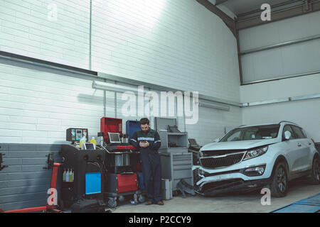 Mechanic using mobile phone while repairing car Stock Photo