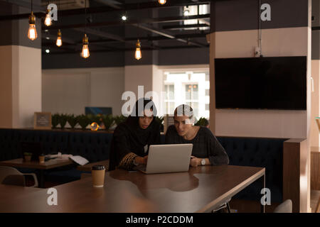 Business colleagues using laptop in cafeteria Stock Photo