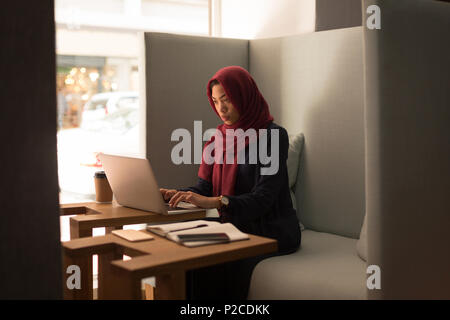 Businesswoman in hijab using laptop at cafeteria Stock Photo