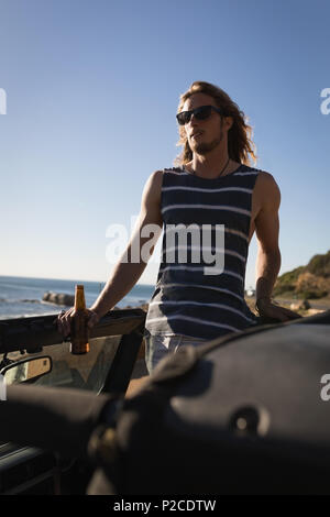 Man having beer in the jeep at beach Stock Photo