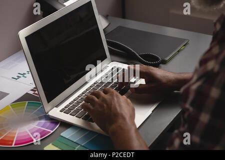 Senior graphic designer using laptop at desk Stock Photo