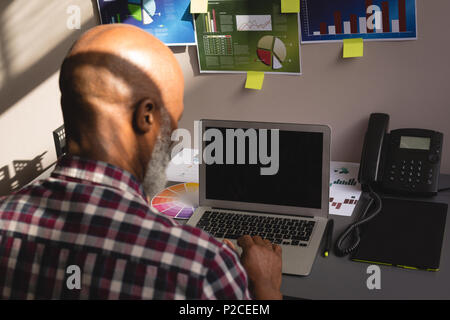 Senior graphic designer using laptop at desk Stock Photo