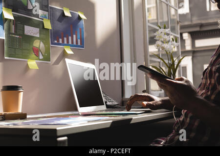 Senior graphic designer using laptop and mobile phone Stock Photo