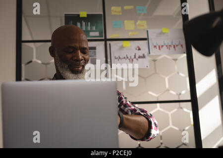 Senior graphic designer using laptop at desk Stock Photo