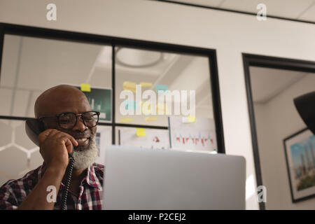 Senior graphic designer talking on landline phone Stock Photo