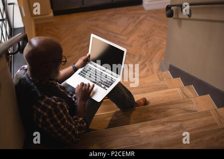 Senior graphic designer using laptop at stairs Stock Photo