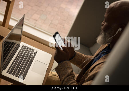 Senior graphic designer using laptop in cafeteria Stock Photo