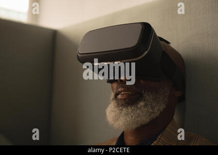 Senior graphic designer using virtual reality headset in cafeteria Stock Photo