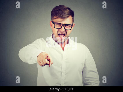 Casual man in glasses and white shirt pointing at camera and screaming in blame and accuse Stock Photo