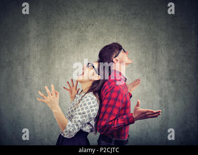 Side view of man and woman in glasses standing back to back screaming in frustration Stock Photo