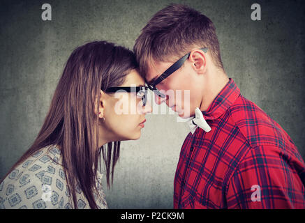 Side view of young man and woman head to head looking with hatred at each other having argument Stock Photo