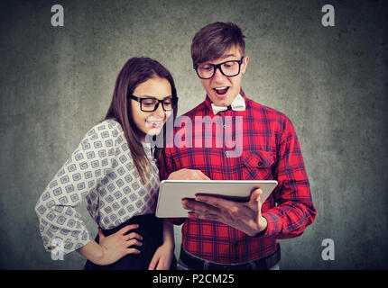 Casual and and woman in glasses exploring modern touchpad looking super excited on gray background Stock Photo