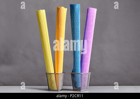 Four rolls of crumpled corrugated paper of different colors, twisted into rolls and placed vertically in metal baskets. Stock Photo