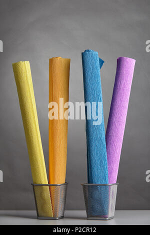 Four rolls of wrinkly corrugated paper of multy colors, twisted into rolls and placed vertically in metal baskets. Stock Photo