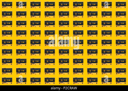 Seamless pattern background of audio cassettes on bright yellow backdrop, minimalistic retro style top view composition Stock Photo