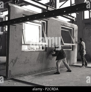 1960s, adult male workers plastering and finishing large precast concrete wall and window panels for installing into the many modern high-rise buildings being constructed at this time across Britain. Stock Photo