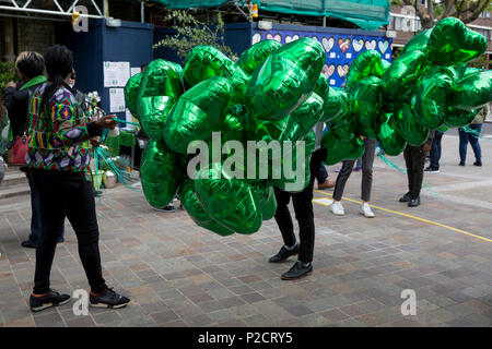 Green heart-shaped balloons during the memorial service for the Grenfell fire on the first anniversary of the tower block disaster, on 14th June 2018, in London, England. 72 people died when the tower block in the borough of Kensington & Chelsea were killed in what has been called the largest fire since WW2. The 24-storey Grenfell Tower block of public housing flats in North Kensington, West London, United Kingdom. It caused 72 deaths, out of the 293 people in the building, including 2 who escaped and died in hospital. Over 70 were injured and left traumatised. A 72-second national silence was Stock Photo